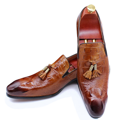Pair of brown leather loafers with tassels on a white background