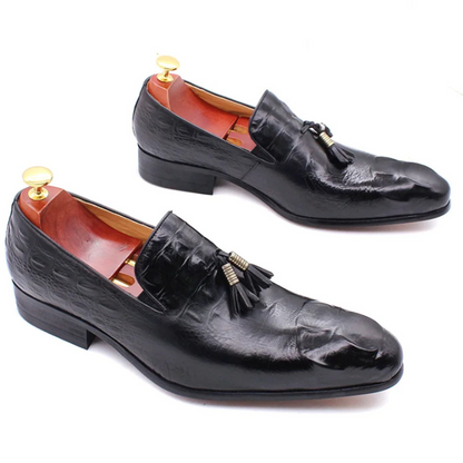 Pair of black leather loafers with tassels on a white background