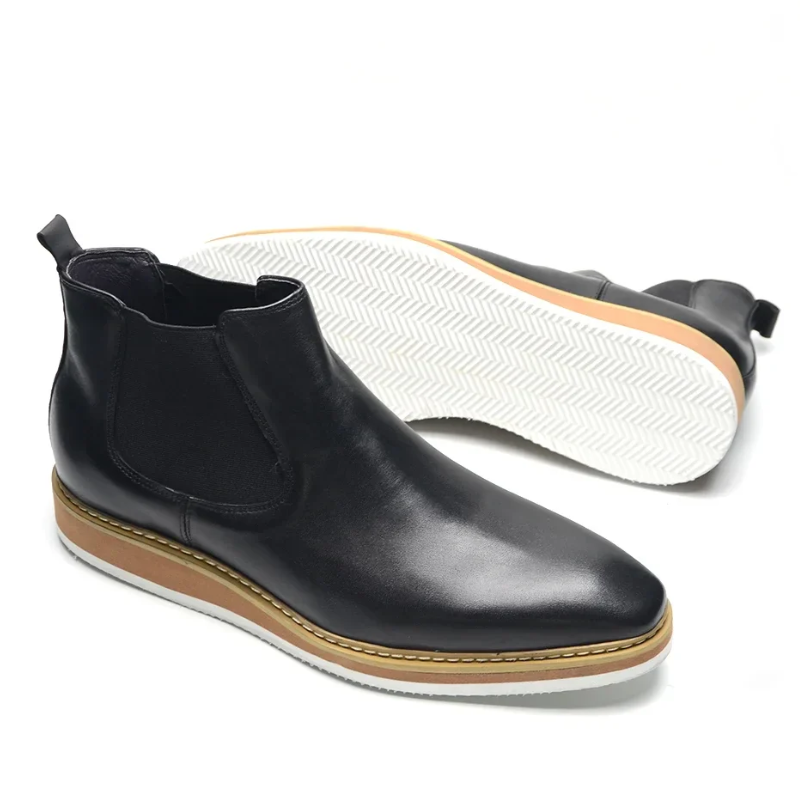 Black Chelsea boot with white sole on a white background